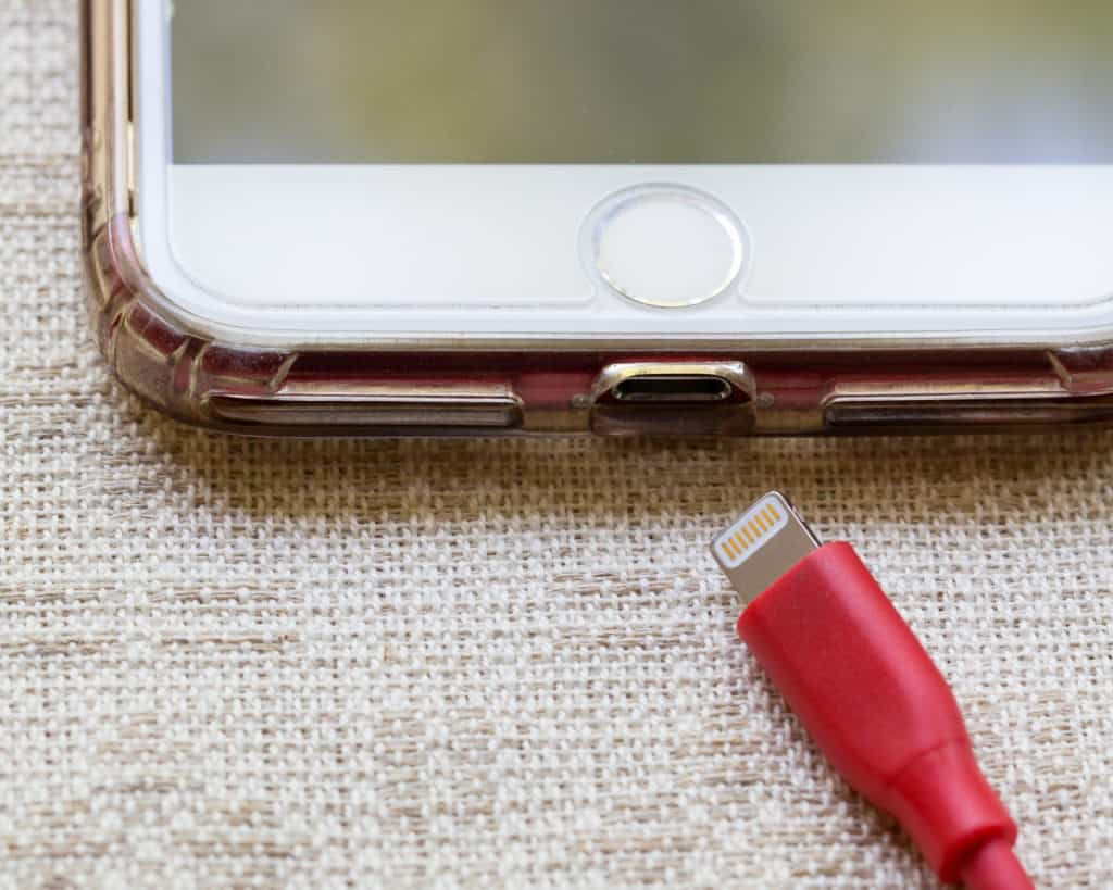 A white iPhone with a red charging colored cable.